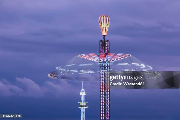 germany, bavaria, munich, aerial view of illuminated chain swing ride spinning against purple sky at dusk - karusell stock-fotos und bilder