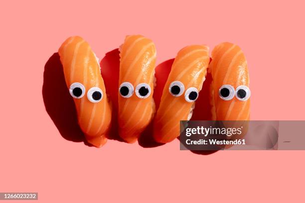studio shot of salmon nigirizushi pieces with googly eyes - wackelaugen stock-fotos und bilder
