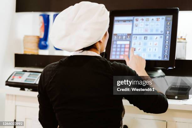 female baker using cash register at bakery - black woman on cash register stock-fotos und bilder