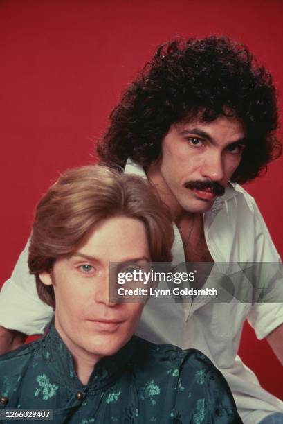 American rock and soul duo Hall & Oates posing in a studio portrait against a red background, 1980.