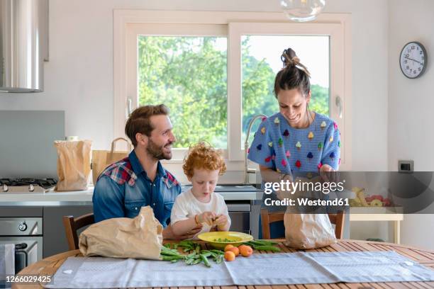 boy with smiling parents in kitchen at home - young man groceries kitchen stockfoto's en -beelden