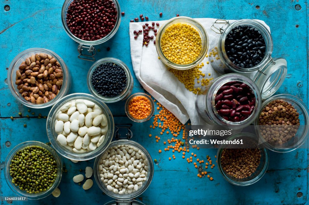 Various beans and lentils in jars on bluerustic wooden surface
