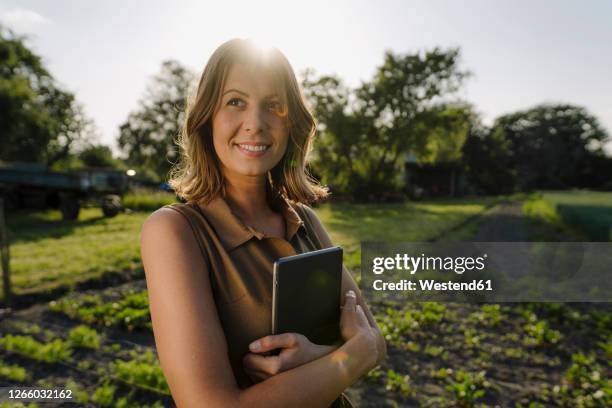 smiling young woman holding tablet on a farm in the countryside - digitalization stock pictures, royalty-free photos & images