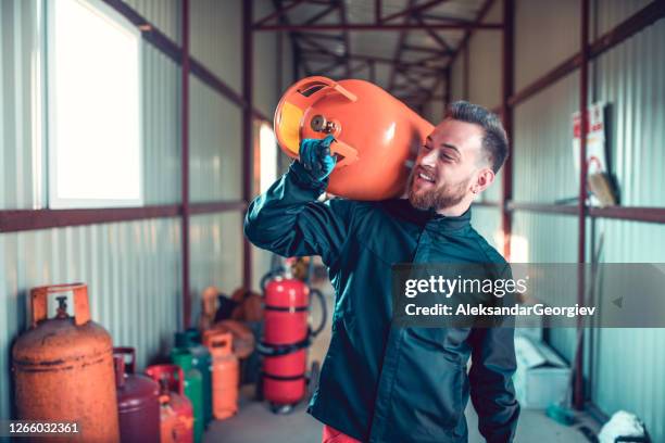 smiling male carrying gas cylinder on shoulder - canister stock pictures, royalty-free photos & images