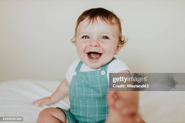 close-up of baby girl laughing while sitting on bed at home - baby close up bed photos et images de collection