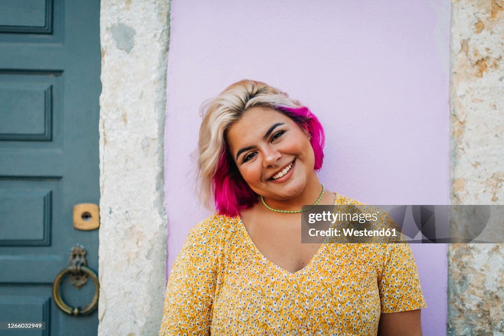 Smiling young woman standing against wall