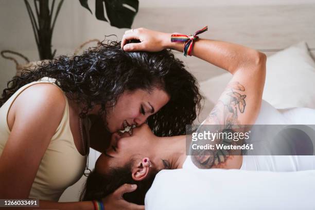 close-up of female couple kissing in bedroom at home - lesbian bed stock pictures, royalty-free photos & images