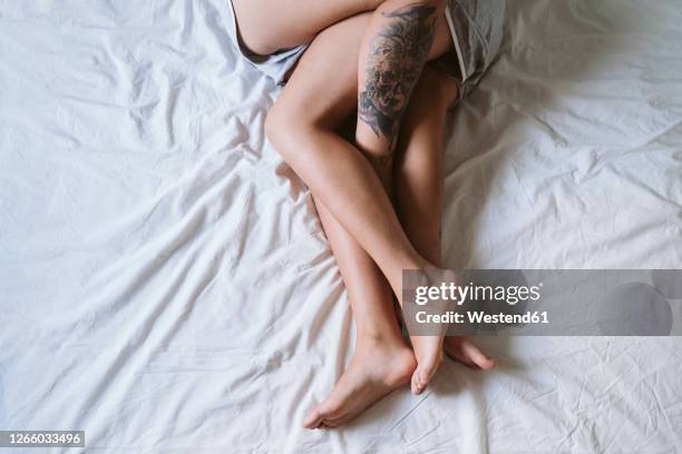 lesbian couple legs lying on bed at home - couple in bed ストックフォトと画像