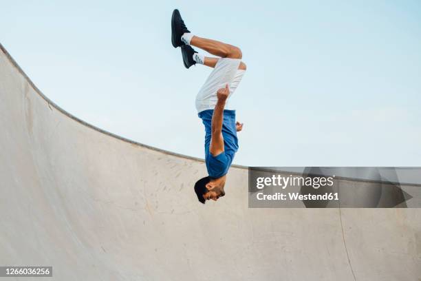 upside down of young man doing wallflip on sports ramp against sky - 逆さ ストックフォトと画像