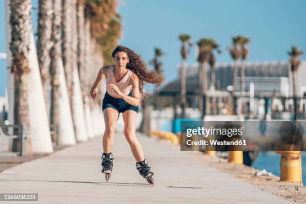 young woman inline skating on promenade at the coast - blade stock pictures, royalty-free photos & images