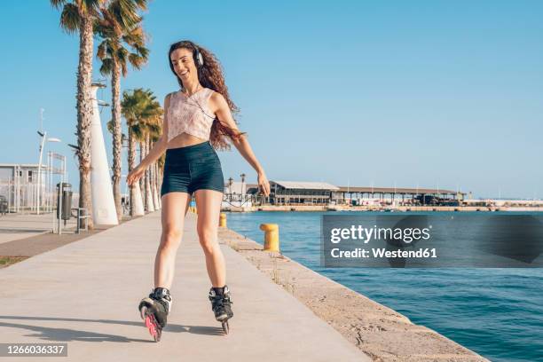 young woman inline skating on promenade at the coast - alicante stock pictures, royalty-free photos & images