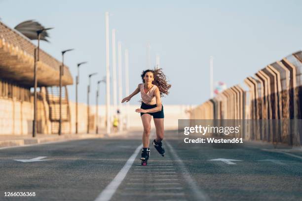 young woman inline skating on boardwalk at the coast - patín en línea fotografías e imágenes de stock