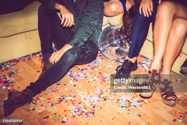 friends sitting on sofa and floor covered in party - bedecken stock-fotos und bilder