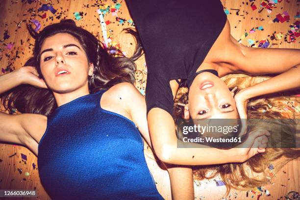 female friends lying on floor covered with confetti in party - confetti floor stockfoto's en -beelden