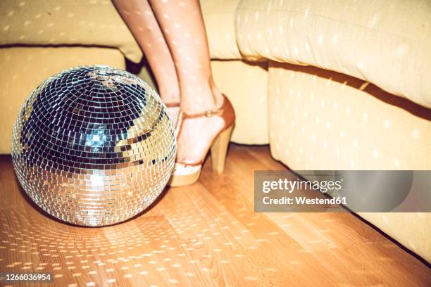 young woman wearing high heels standing by disco ball on floor in party - silver shoe stockfoto's en -beelden