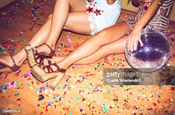 female friends sitting on floor covered with confetti in party - diskokugel stock-fotos und bilder