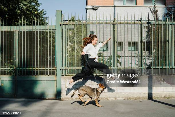 woman running with dog at sidewalk in city - 犬　走る ストックフォトと画像