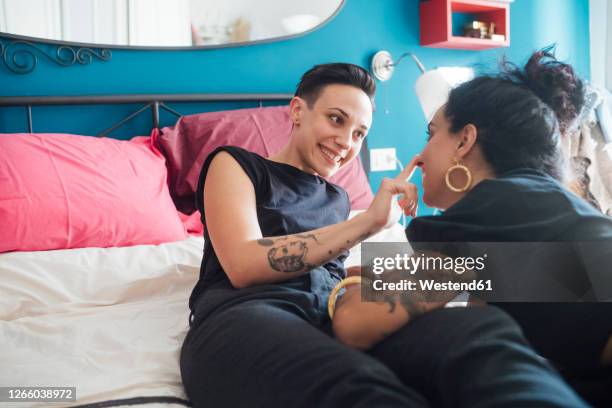 smiling woman talking to partner in bedroom - lesbian bed stock pictures, royalty-free photos & images