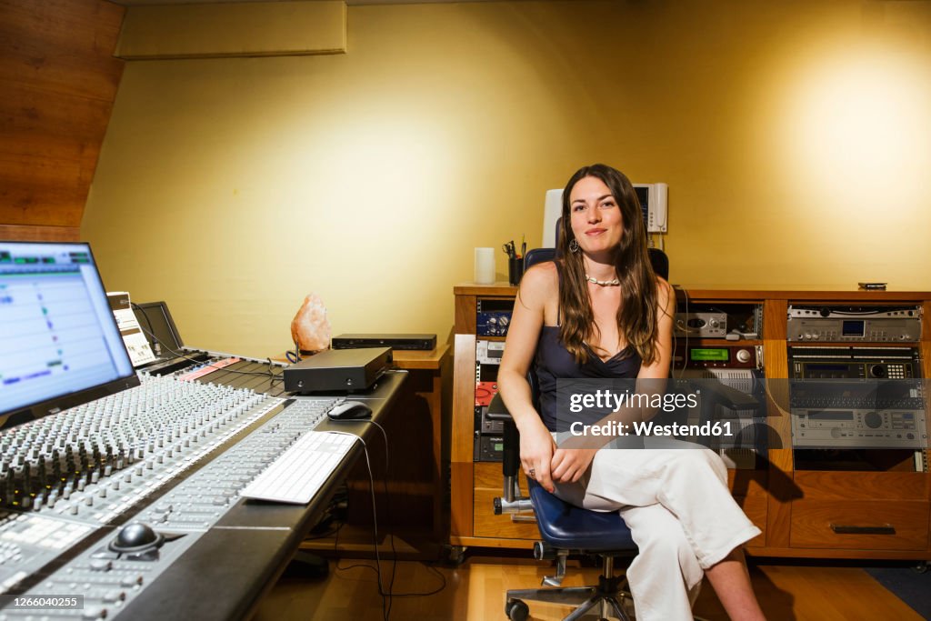 Smiling female singer sitting in recording studio