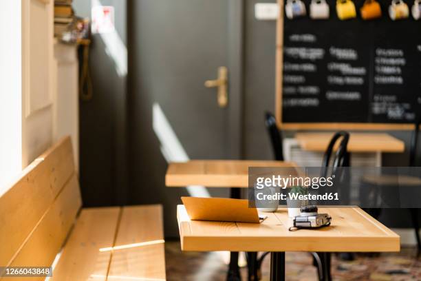 book and camera on wooden table in modern coffee shop - espacio pequeño fotografías e imágenes de stock