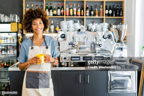 happy female barista holding coffee mug in cafe - barista stock pictures, royalty-free photos & images