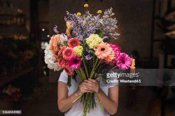 female florist holding colorful flowers while standing in shop - large group of craftsman stock-fotos und bilder