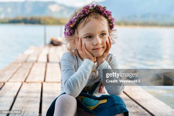 close-up of cute girl wearing tiara sitting on jetty against lake - diadema fotografías e imágenes de stock