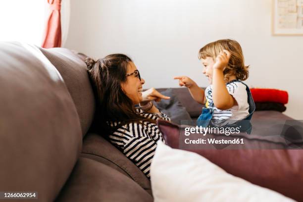 happy mother and daughter talking while relaxing on sofa at home - happy toddler stockfoto's en -beelden