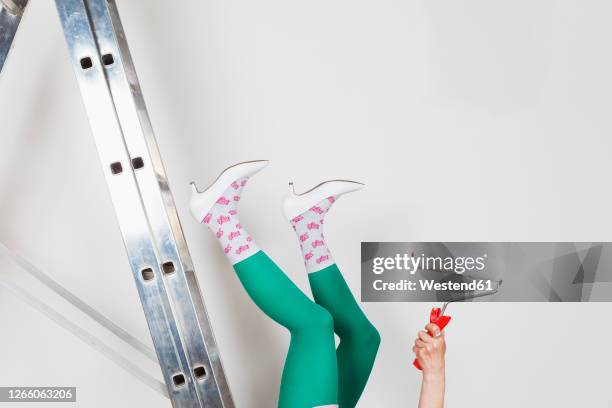 mature woman falling from ladder during painting walls at home - legs in stockings stock-fotos und bilder