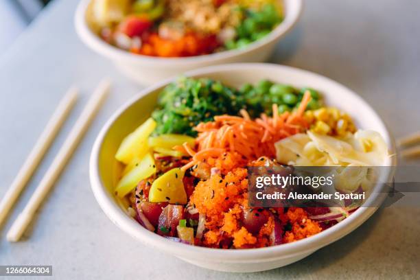 close up of poke bowl with salmon, tuna and various vegetables served in a recyclable paper plate - pokes stock pictures, royalty-free photos & images