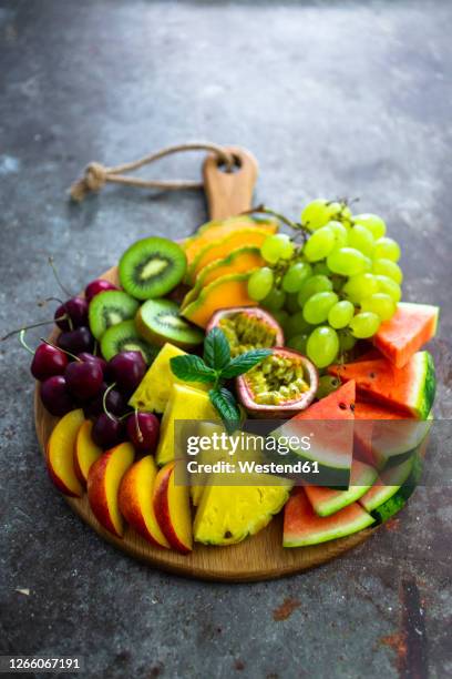 fruit salad with watermelon, kiwi, passion fruit, grape, cherry, peach and melon on chopping board - fruit salad stock pictures, royalty-free photos & images