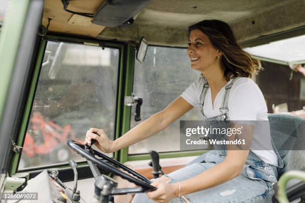 happy young woman driving tractor - traktor stock-fotos und bilder
