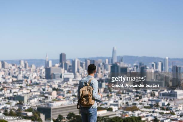 young man with backpack looking at san francisco skyline, rear view, california, usa - central california - fotografias e filmes do acervo
