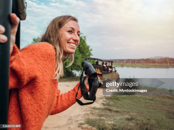 jeune femme heureuse sur le safari de luxe recherchant des animaux sauvages dans la jungle utilisant des jumelles - safari animals stock photos et images de collection