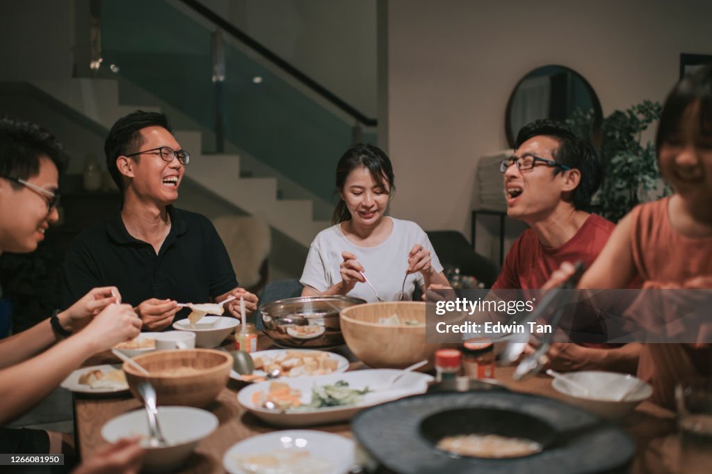 An asian chinese families and friends having night dinner gathering at home with traditional chinese steamboat dishes