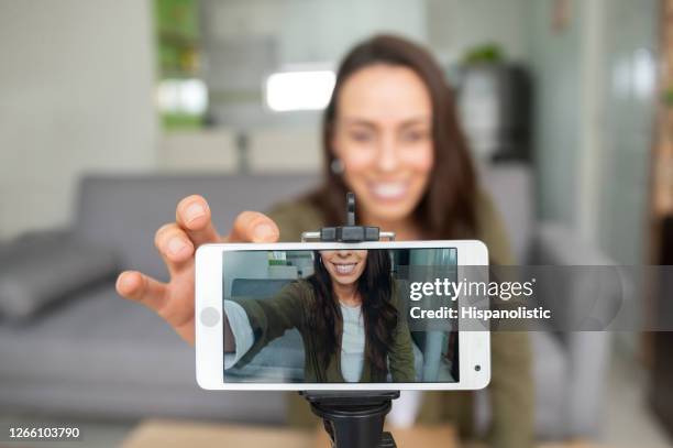 happy female vlogger recording content at home using her cell phone - filmar imagens e fotografias de stock