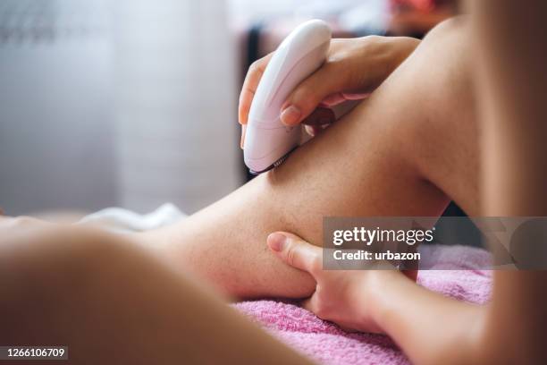 mujer afeitando las piernas con depilador - waxing hair removal fotografías e imágenes de stock