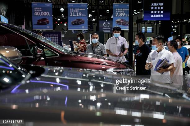 Exhibition staff and attendees wear protective masks as they look around the Volkswagen stand booth at the 18th Central China International Auto Show...