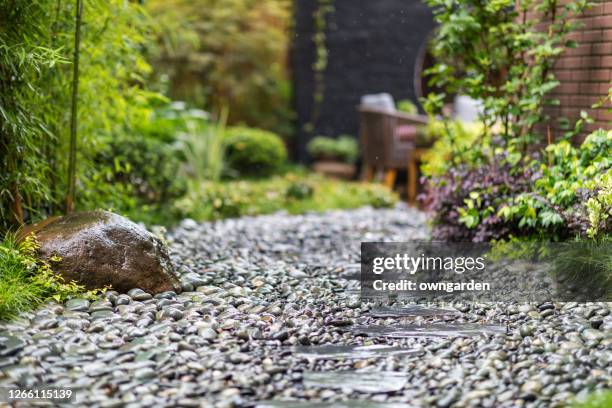 decorative sprinkling of flowerbed paths with pebbles - pebbles stockfoto's en -beelden