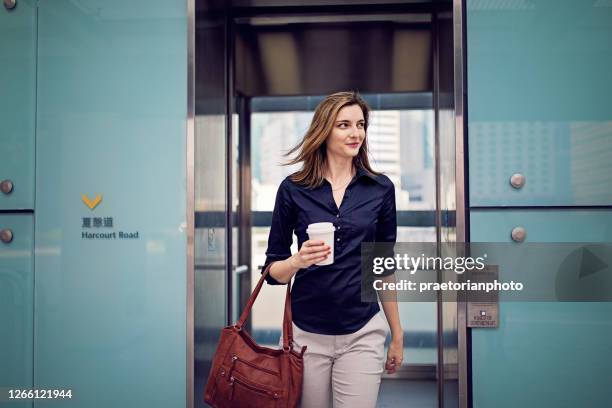 joven empresaria está saliendo de ascensor yendo a su oficina - woman leaving fotografías e imágenes de stock