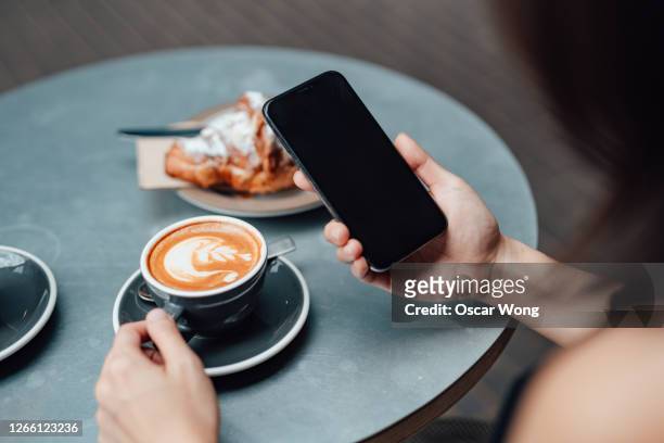 close-up shot of young woman using smart phone at cafe - cafe culture uk stock pictures, royalty-free photos & images
