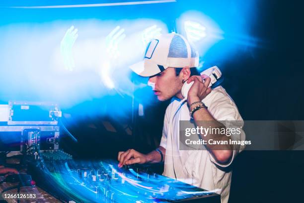 dj with headphones at night club party under the blue light and people crowd in background - club dj 個照片及圖片檔