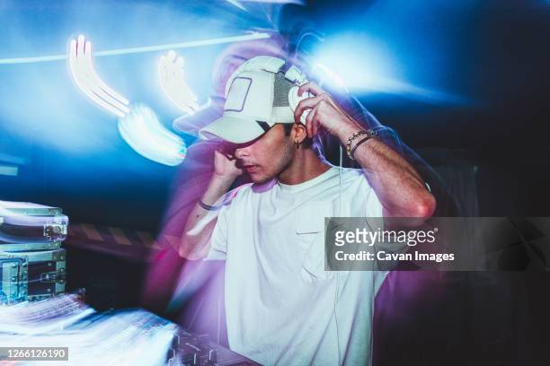 dj with headphones at night club party under the blue light and people crowd in background - cd ストックフォトと画像