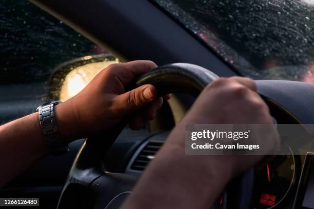 close-up of a man driving with his hands on the wheel - hand steering wheel stock pictures, royalty-free photos & images