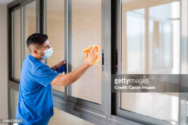 cleaning staff disinfecting the windows to avoid covid19 - hauswart stock-fotos und bilder