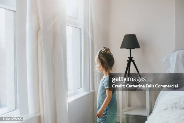 little girl gazing dreamily out a sunny bedroom window - príncipe encantado imagens e fotografias de stock