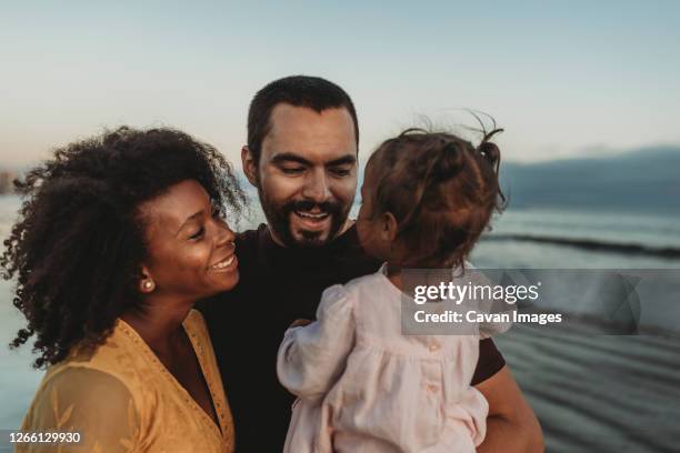 young family embracing at the beach - amerikaner mit mexikanischer herkunft stock-fotos und bilder