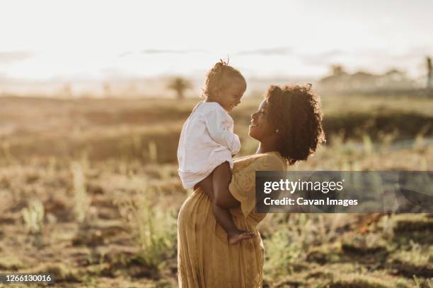 pregnant mother holding young toddler girl on belly at beach - one and a half summer stock pictures, royalty-free photos & images