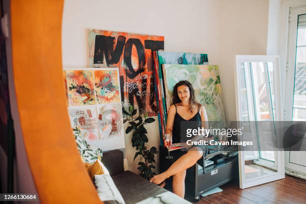 artist sitting in home studio surrounded by canvas and paintings - painted image paintings art stock pictures, royalty-free photos & images