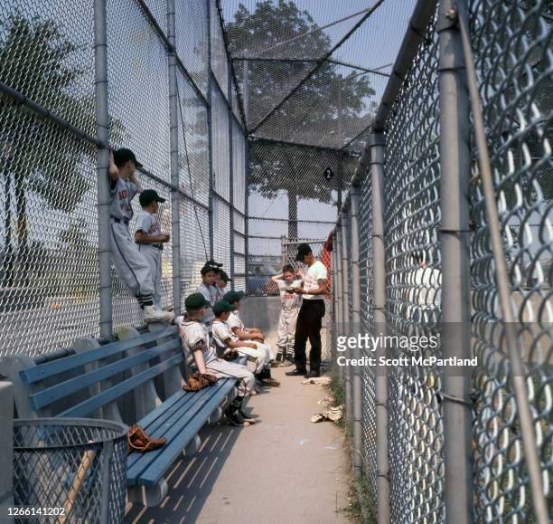View of players from a Boys Club Of Corona little league baseball team, with their coach, in the dugout prior to a game at Flushing Meadows Park, in...